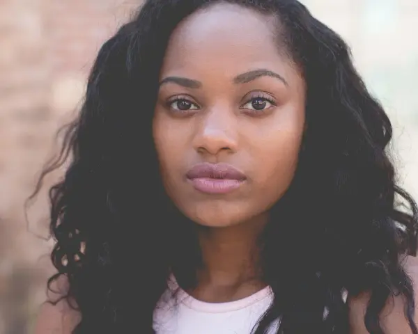 Primer plano de una mujer joven con cabello oscuro y rizado, ojos marrones y labios rosados. Imágenes de personas sin derechos de autor.