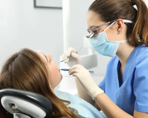 Dentista revisa la boca de una paciente. ¿Cuántos años son la carrera de odontología?