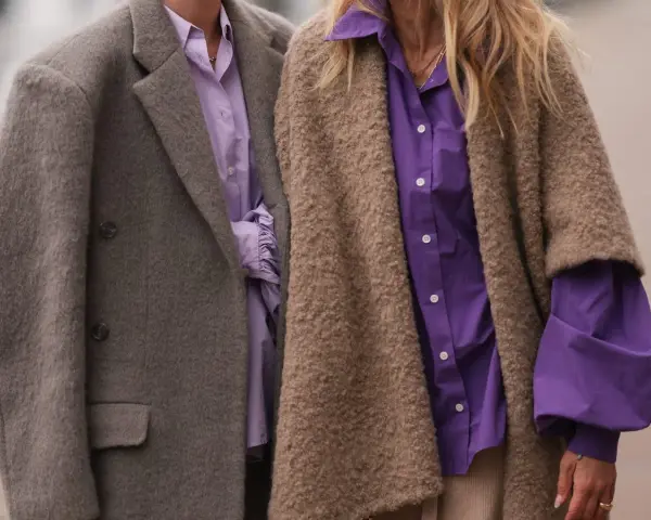 Dos personas con abrigos y camisas moradas. Un ejemplo de que es la fast fashion: ropa barata y de moda rápida.
