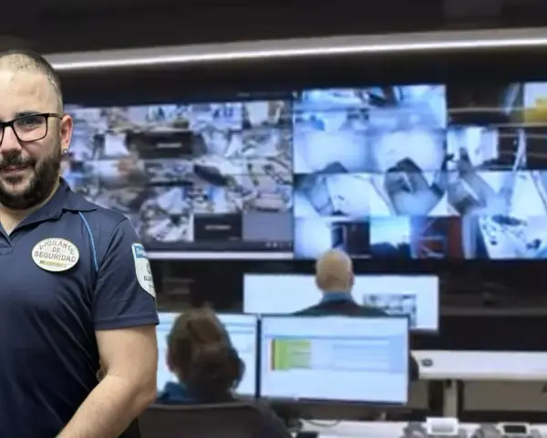 Vigilante de seguridad con certificado de discapacidad, sonriendo ante cámaras de vigilancia.