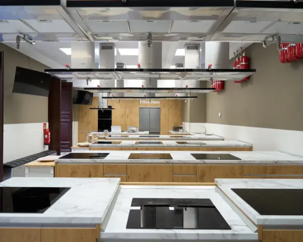 Cocina moderna equipada para una carrera de gastronomía, con encimeras de mármol, placas de inducción y campanas extractoras.
