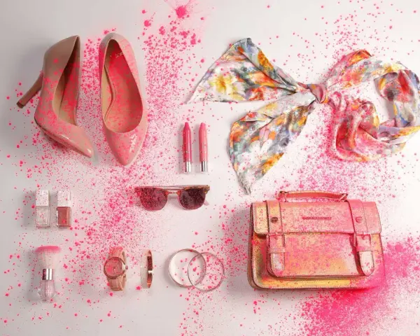 Zapatos, bolso, pañuelo, labiales, gafas de sol y accesorios de moda salpicados de polvo rosa.