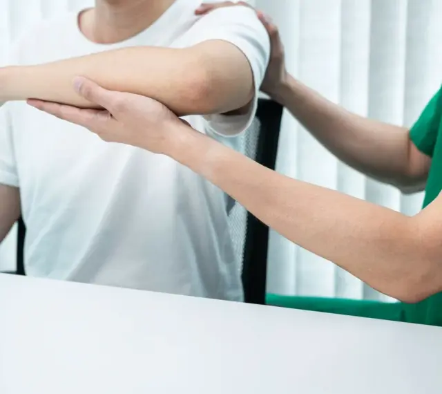 Fisioterapeuta ayuda a paciente con banda elástica. Averigua cuanto cobra un fisioterapeuta por sesión.