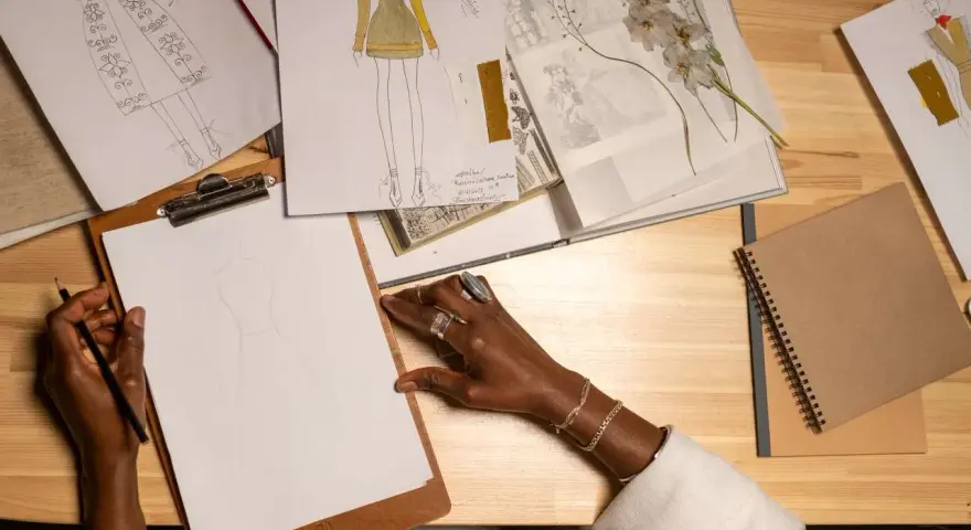 Manos dibujando bocetos de moda, inspirada para estudiar diseño de moda.