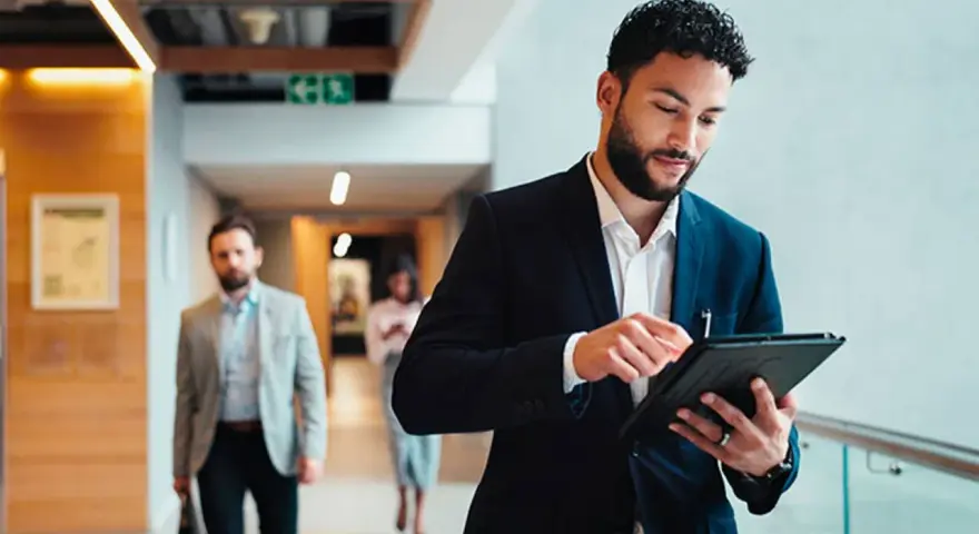 Hombre de negocios revisa su tablet, preparándose para sus dobles grados con relaciones internacionales.