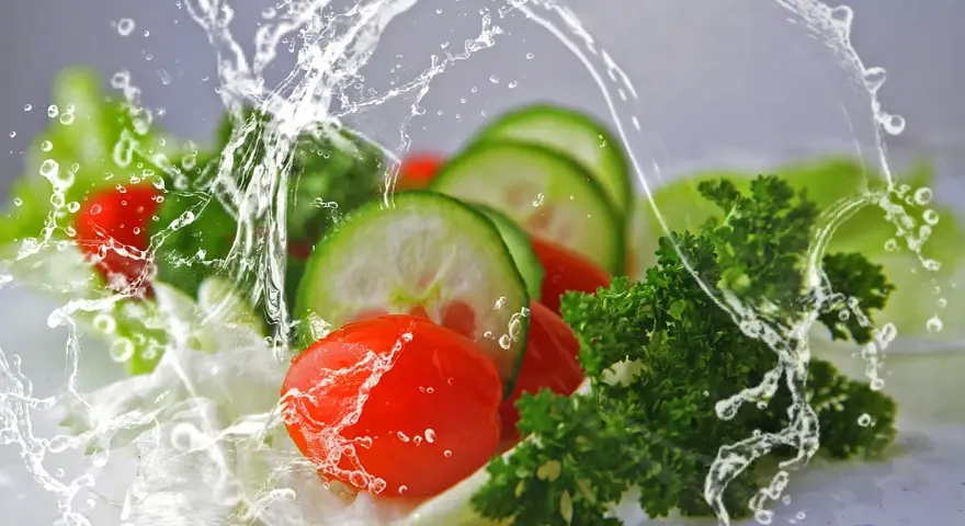 Frescos tomates, pepinos y perejil salpicados por agua. Una imagen que inspira una vida saludable y una dietética a distancia.