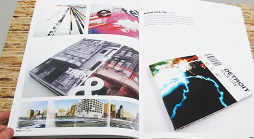 Un portfolio de diseño gráfico muestra una revista abierta con imágenes de arquitectura y arte abstracto, y un folleto de "Detroit rock city".