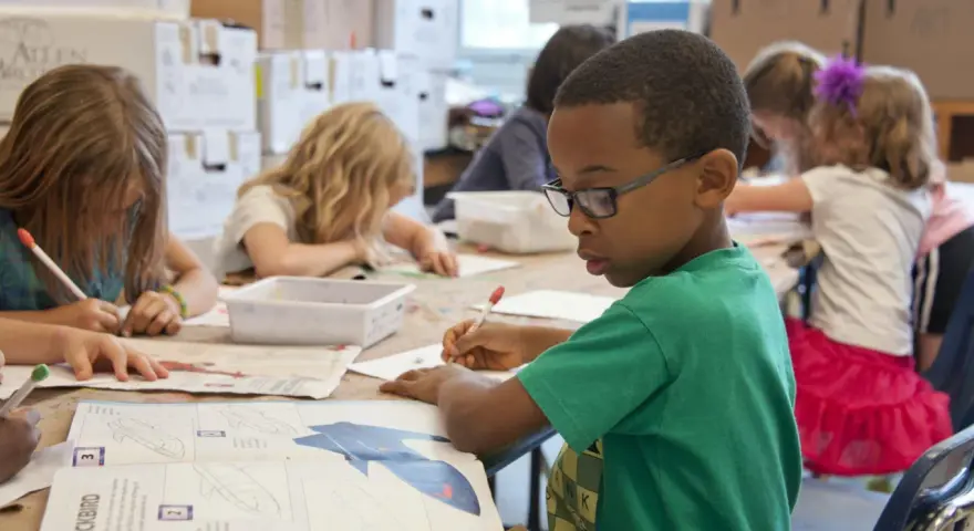 Niños concentrados en una actividad artística, guiados por un técnico superior en educación infantil.