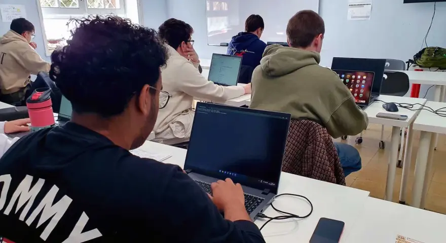 Estudiantes de **grado medio informática** concentrados frente a sus ordenadores en un aula.