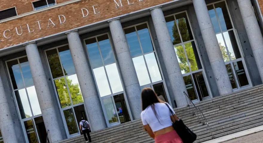 Fachada de la Facultad de Medicina, con estudiantes subiendo escaleras. Un futuro médico se dirige a una de las universidades privadas de medicina.