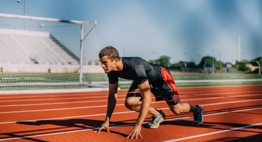Atleta en posición de salida en pista de atletismo. ¿Cuánto cobra un profesor de educación física?