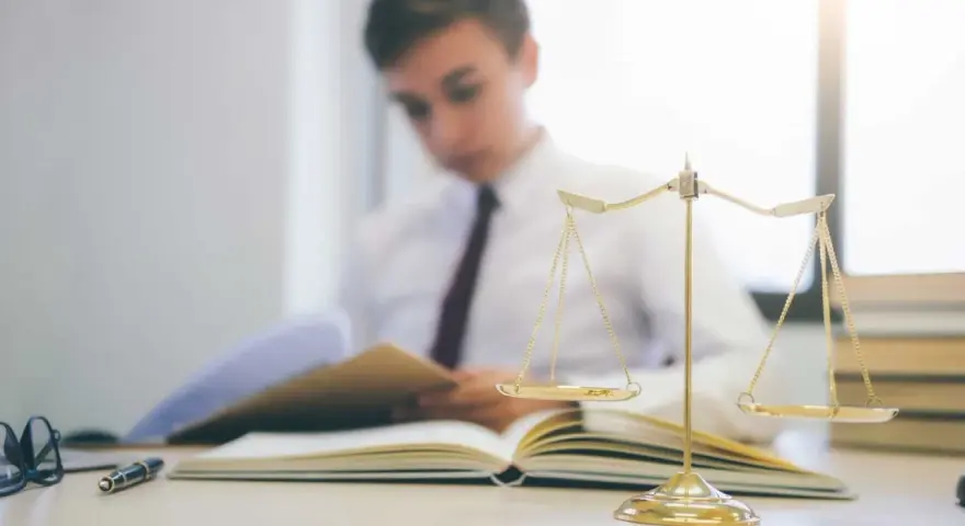 Estudiante de derecho concentrado en sus estudios, con una balanza de la justicia y libros. Averigua cuanto dura la carrera de derecho.