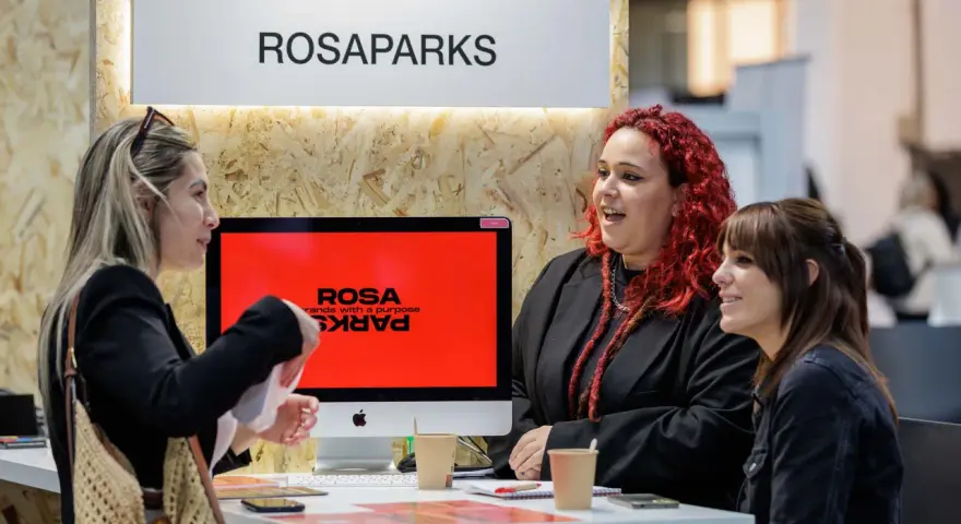 Tres mujeres conversan en un stand de ROSAPARKS, un evento de marketing en Barcelona.
