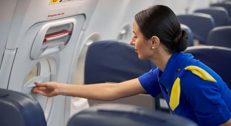 Una azafata de vuelo revisa un compartimento en el avión.