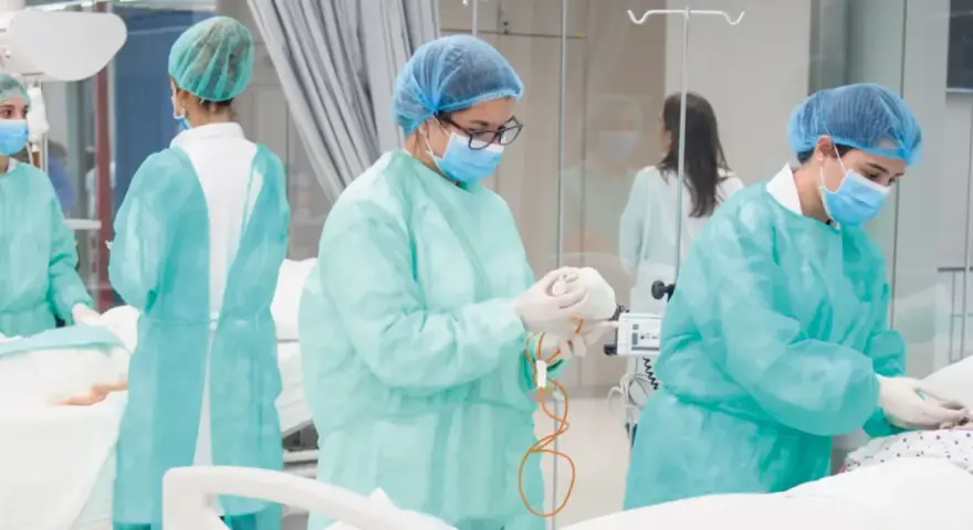 Estudiantes de enfermería en universidades privadas practican en un entorno clínico, vestidas con batas y mascarillas.