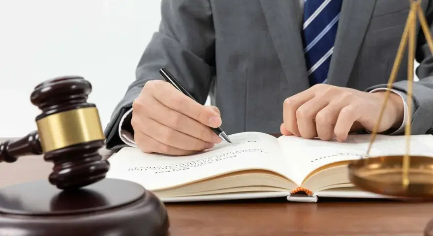 Un juez con toga y corbata escribe en un libro. A su lado, un mazo y la balanza de la justicia. ¿Cuánto cobra un juez en España?