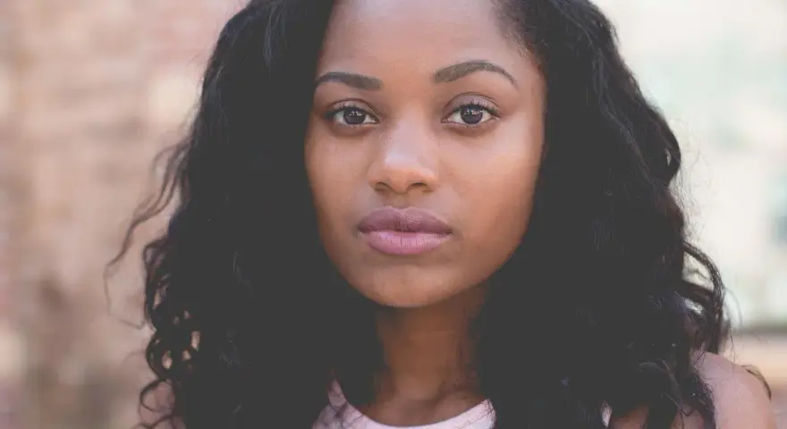 Primer plano de una mujer joven con cabello oscuro y rizado, ojos marrones y labios rosados. Imágenes de personas sin derechos de autor.