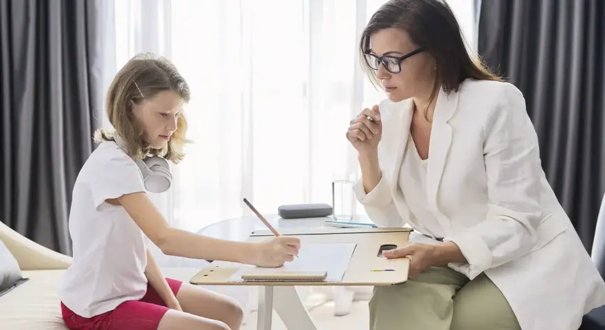 Psicóloga atenta a una niña que dibuja. La sesión es parte de la terapia infantil, y la pregunta de cuánto cobra un psicólogo en España es clave para acceder a estos servicios.