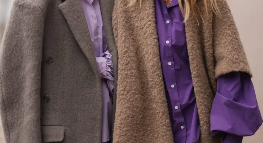 Dos personas con abrigos y camisas moradas. Un ejemplo de que es la fast fashion: ropa barata y de moda rápida.
