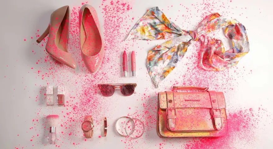 Zapatos, bolso, pañuelo, labiales, gafas de sol y accesorios de moda salpicados de polvo rosa.