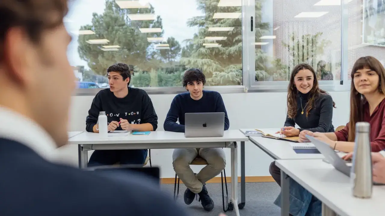 Estudiantes discuten estrategias de marketing digital en un aula.