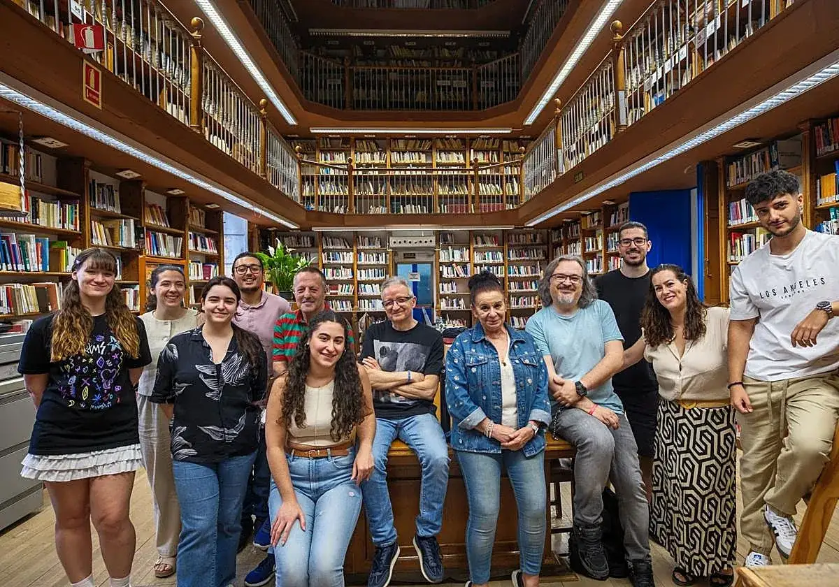 Grupo diverso de personas posando en una biblioteca antigua, rodeados de estanter&iacute;as repletas de libros. Un ambiente ideal para quienes quieren saber qu&eacute; estudiar para ser bibliotecario.
