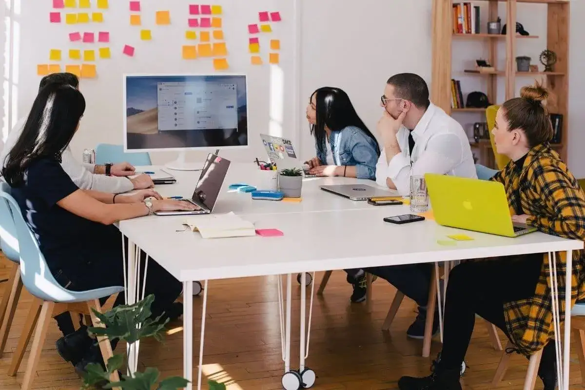 Equipo colaborando en ideas de branding y marketing, con notas adhesivas y laptops en una mesa de reuniones.