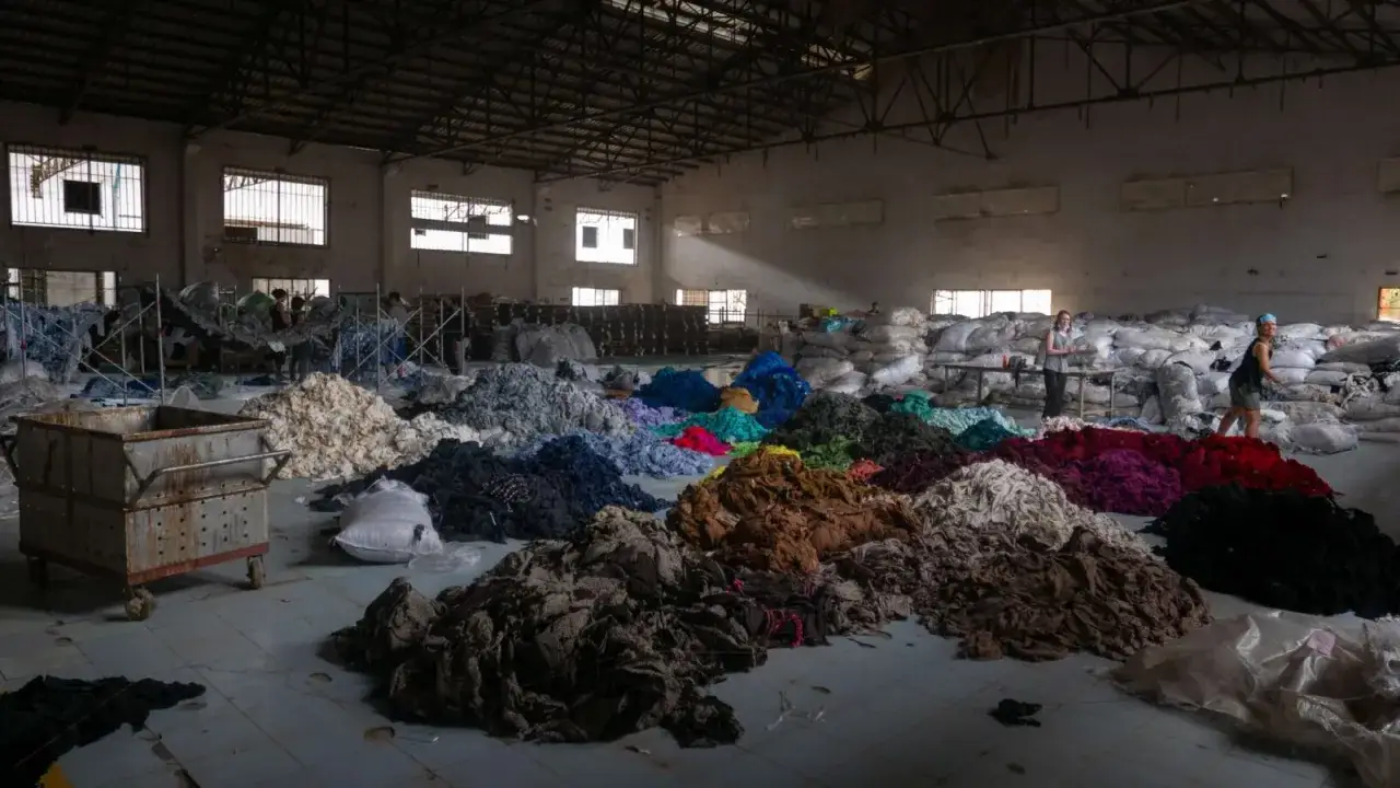 Mont&oacute;n de retazos de tela de colores en un almac&eacute;n, reflejo de que es la fast fashion y su impacto.