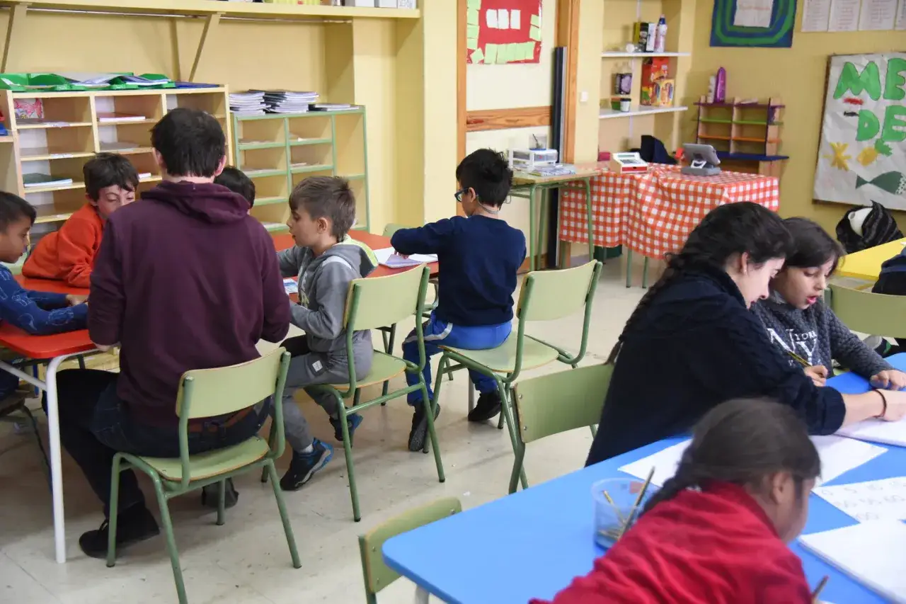 Niños y adultos trabajando juntos en un aula, promoviendo la integración social y el aprendizaje colaborativo.