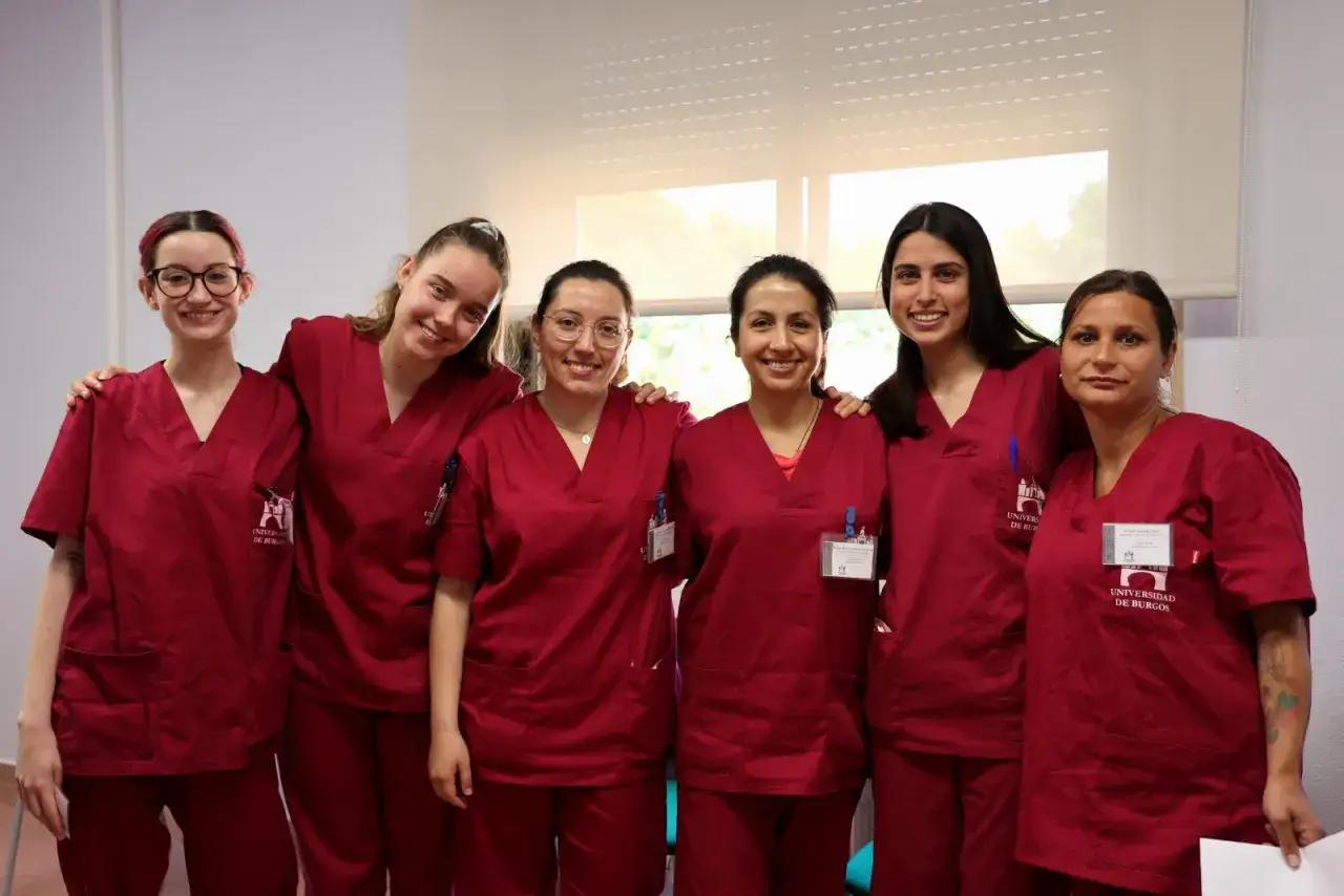 Seis estudiantes sonr&iacute;en, vestidas con uniformes de terapia ocupacional carrera.