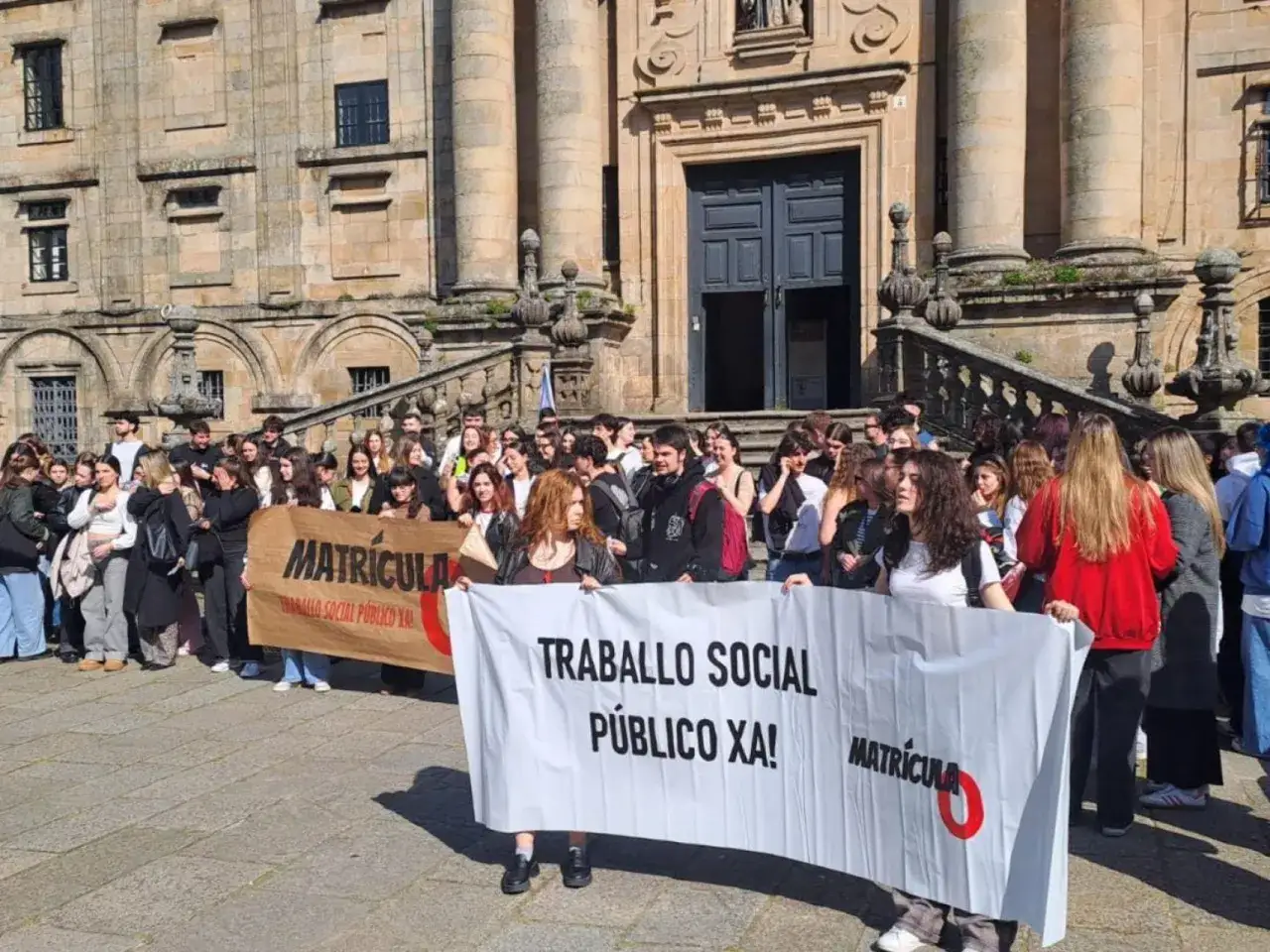 Estudiantes protestan frente a un edificio histórico, exigiendo matrícula para cursos gratuitos de trabajo social.