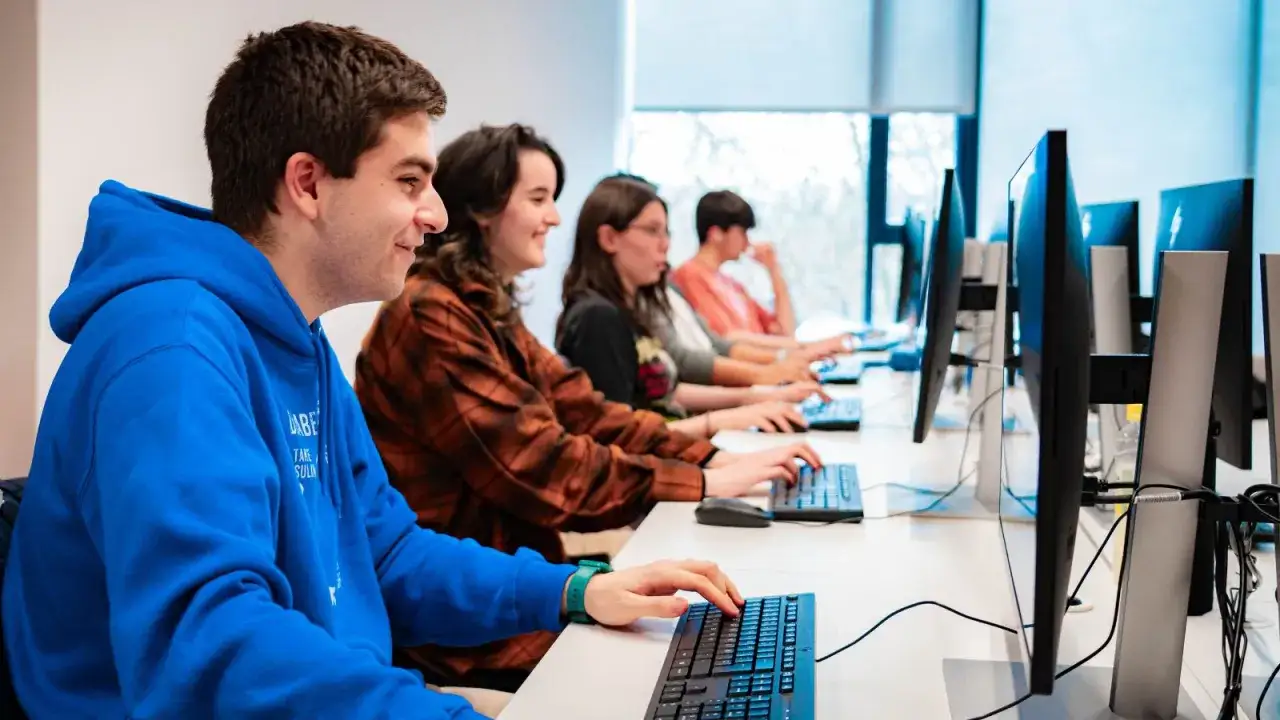 Estudiantes concentrados en sus ordenadores, aprendiendo fp online informatica.