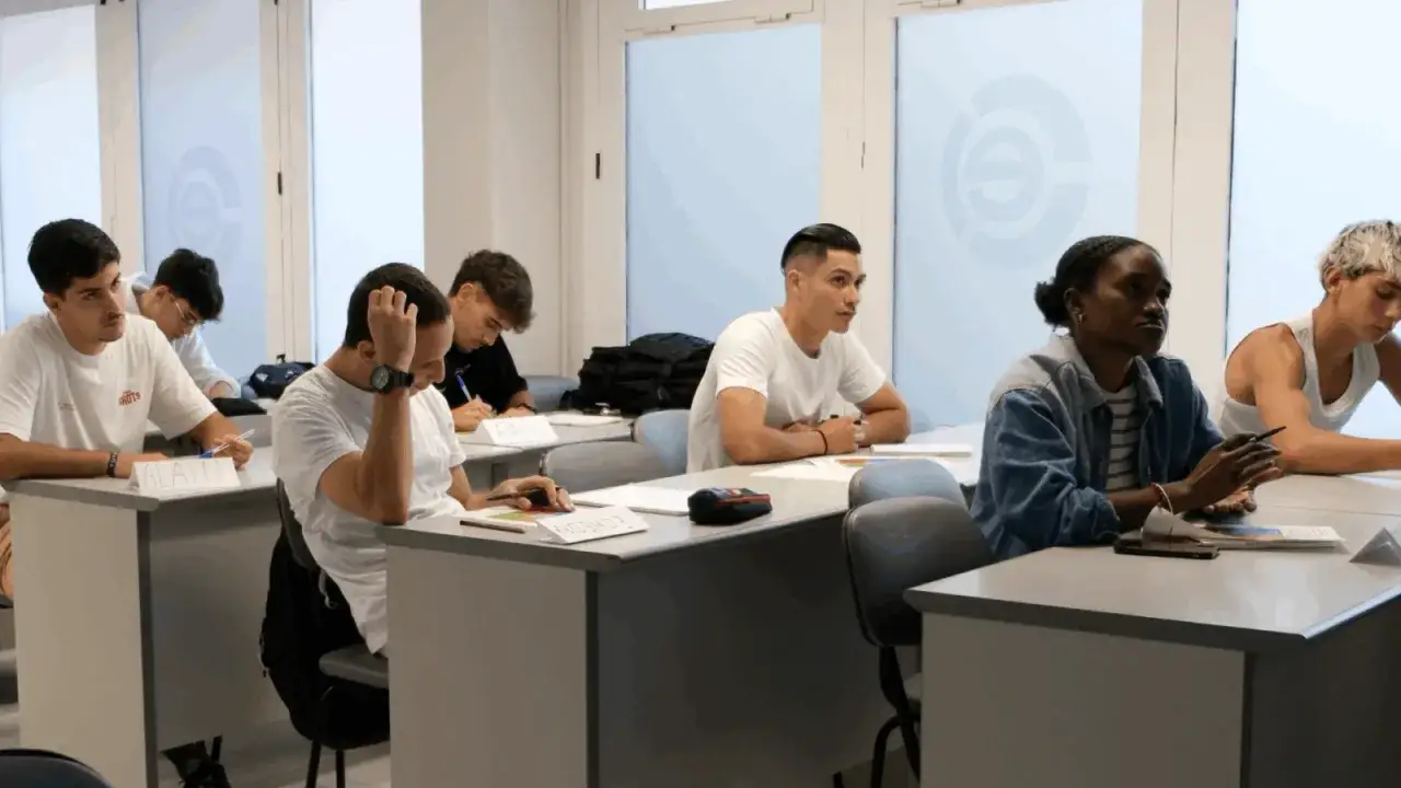 Estudiantes en un aula, participando en una formación en centros de trabajo. Se observan atentos, tomando notas y escuchando.