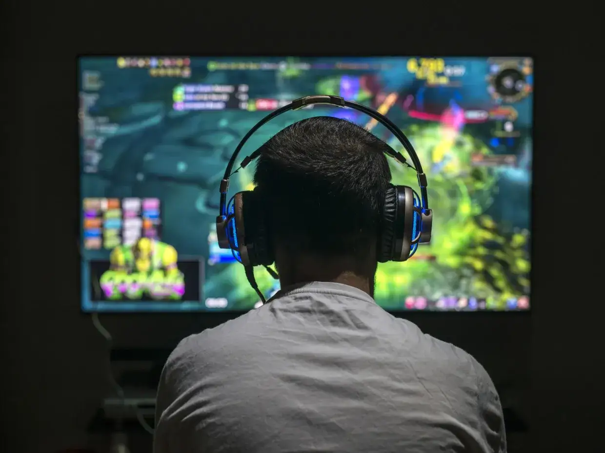 Persona con auriculares jugando en pantalla grande. ¿Cuánto cobra un programador de videojuegos?