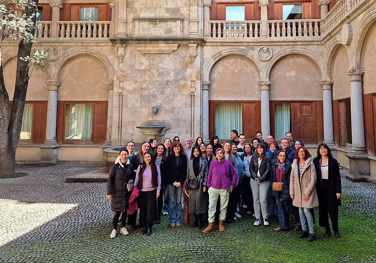 Grupo de personas posando en un patio histórico, celebrando la obtención de sus grados universitarios.