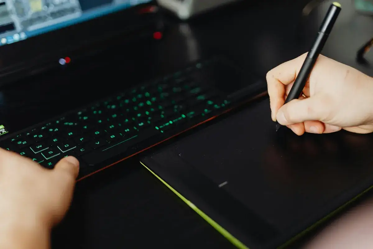 Mano dibujando en tableta gr&aacute;fica junto a teclado iluminado. &iquest;Cu&aacute;nto cobra un dise&ntilde;ador de videojuegos?