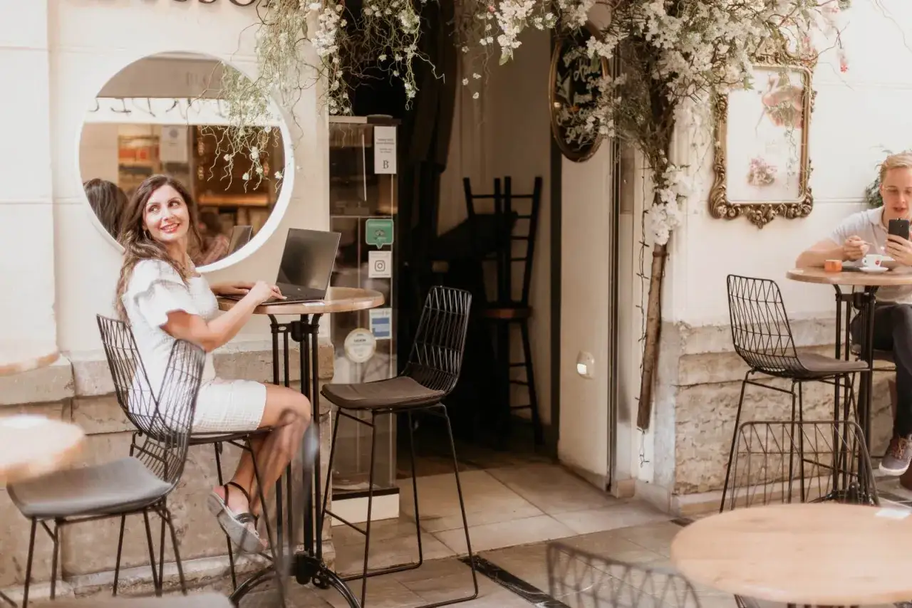 Mujer trabajando en portátil en terraza, reflejando la diferencia entre decorador y diseñador de interiores.