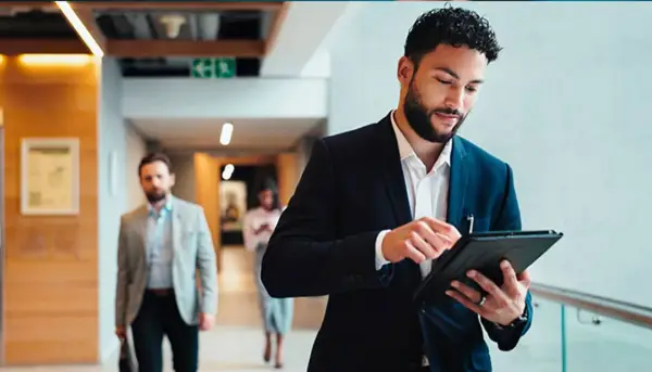 Hombre de negocios revisa su tablet, preparándose para sus dobles grados con relaciones internacionales.