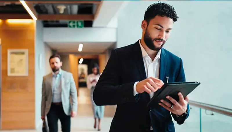 Hombre de negocios revisa su tablet, preparándose para sus dobles grados con relaciones internacionales.