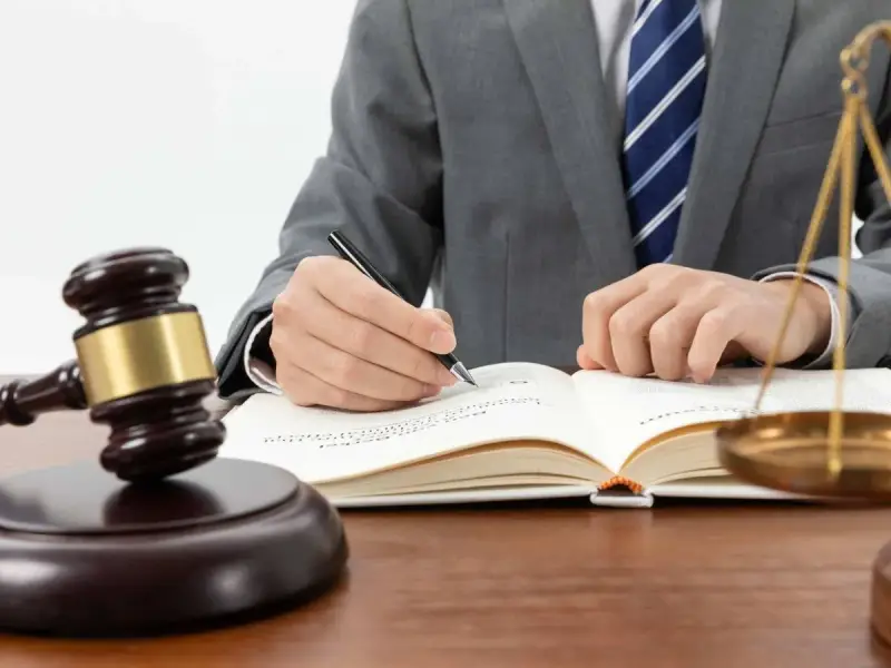 Un juez con toga y corbata escribe en un libro. A su lado, un mazo y la balanza de la justicia. ¿Cuánto cobra un juez en España?