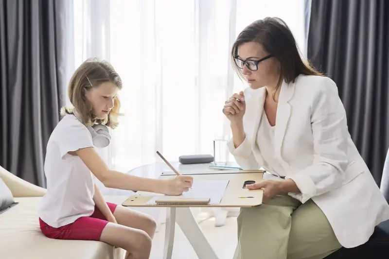 Psicóloga atenta a una niña que dibuja. La sesión es parte de la terapia infantil, y la pregunta de cuánto cobra un psicólogo en España es clave para acceder a estos servicios.